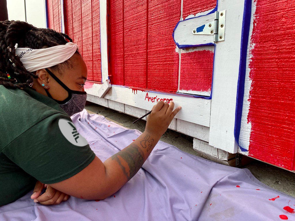 Team leader on her stomach painting a wall