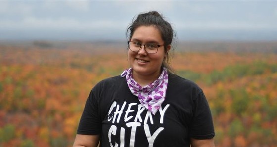 Photo of AmeriCorps member in the VISTA program smiling to camera in a field