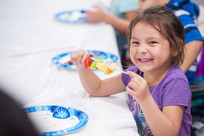 Little Girl smiling eating fruit
