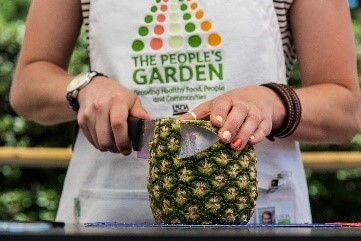 Someone in an apron cutting a pineapple