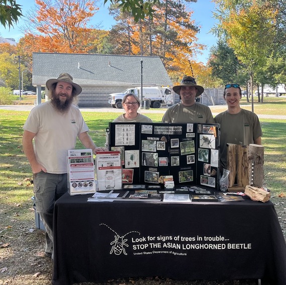 Employees at an outreach event with a table full of outreach material