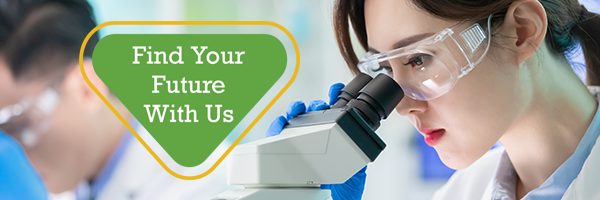 laboratory technician in a lab coat looking into a microscope