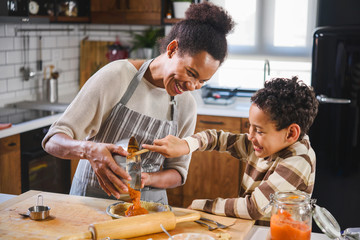 A mother and son making a pumpkin pie in the kitchen. 