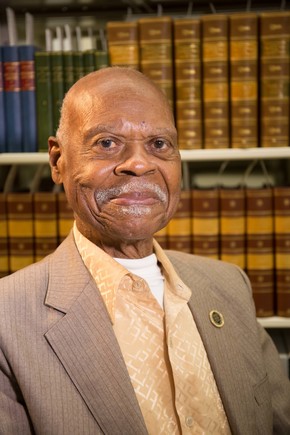 Color portrait of Dr. Ernest James Harris sitting in front of books taken at the oral history