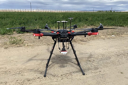 A drone sitting on the ground in front of a field. 