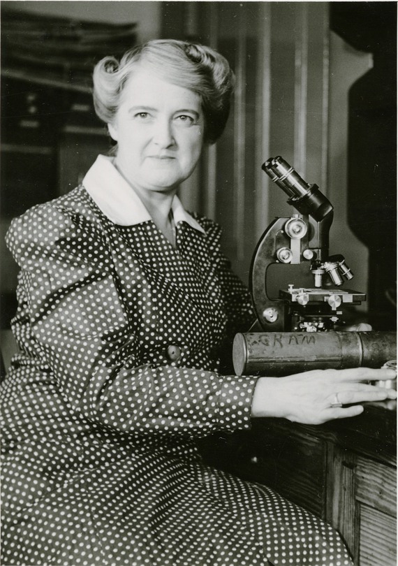 Dr. Cram in a polka dot dress next to a microscope