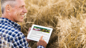 Image of a man holding an ipad showing farmers.gov website