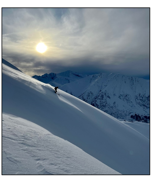 Photo of a man skiing down a snow covered hillside in Alaska