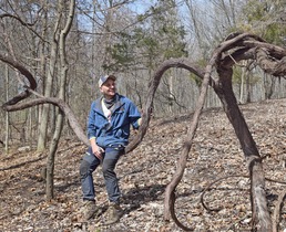 Joshua Chiatovich sits on a grapevine at his family's forest plot in Oakland County.