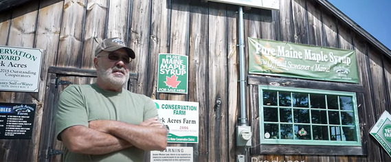 photo of Russell Black in front of his maple syrup store in Maine