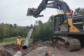 Workers remove a siphon hose that carried water over the Forest Lake dam while a replacement spillway was under construction.