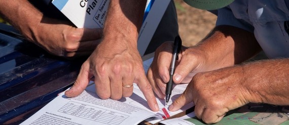 photo of producer signing document with NRCS employee assisting 