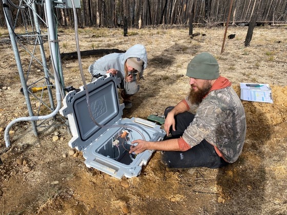 Two people work on a new shelter less monitoring system, which is embedded in the ground.