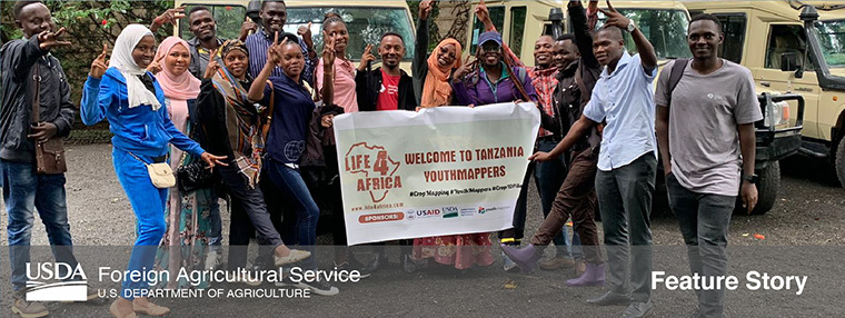 A group of 14 YouthMappers from Tanzania pose in front of jeeps before going out into the field for research
