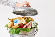 Food Waste and Food Retail Density. Hand Putting Lid On Garbage Can Full Of Waste Food. USDA NIFA Fresh From the Field.