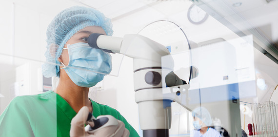 Image of scientist with mask looking through microscope; courtesy of Getty Images.  Links to Funding Opportunity.