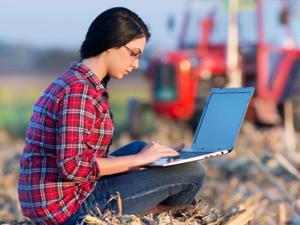 Farmer working on laptop in field, courtesy of Getty Images.