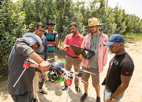 WSU post-doctoral fellow Abhilash Chandel explains to an AgAID Institute team how the drone’s sensing technology. Image courtesy of WSU.