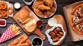 Assorted fatty foods, hamburgers, pizza, fried chicken with sides, courtesy of Getty Images.