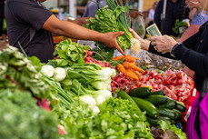 Customer buys fresh produce in local market. Image courtesy of Adobe Stock.