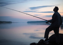 Fisherman fishing on a riverbank, courtesy of Getty Images.
