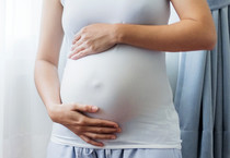 A young pregnant woman holds her belly, courtesy of Adobe Stock.