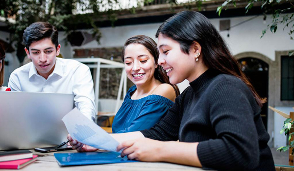 Three students studying at table, courtesy of Adobe Stock.