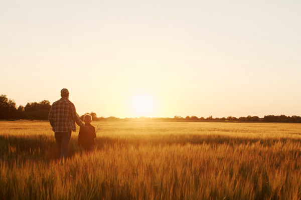 Farmer and child in a field. Image courtesy of Adobe Stock.