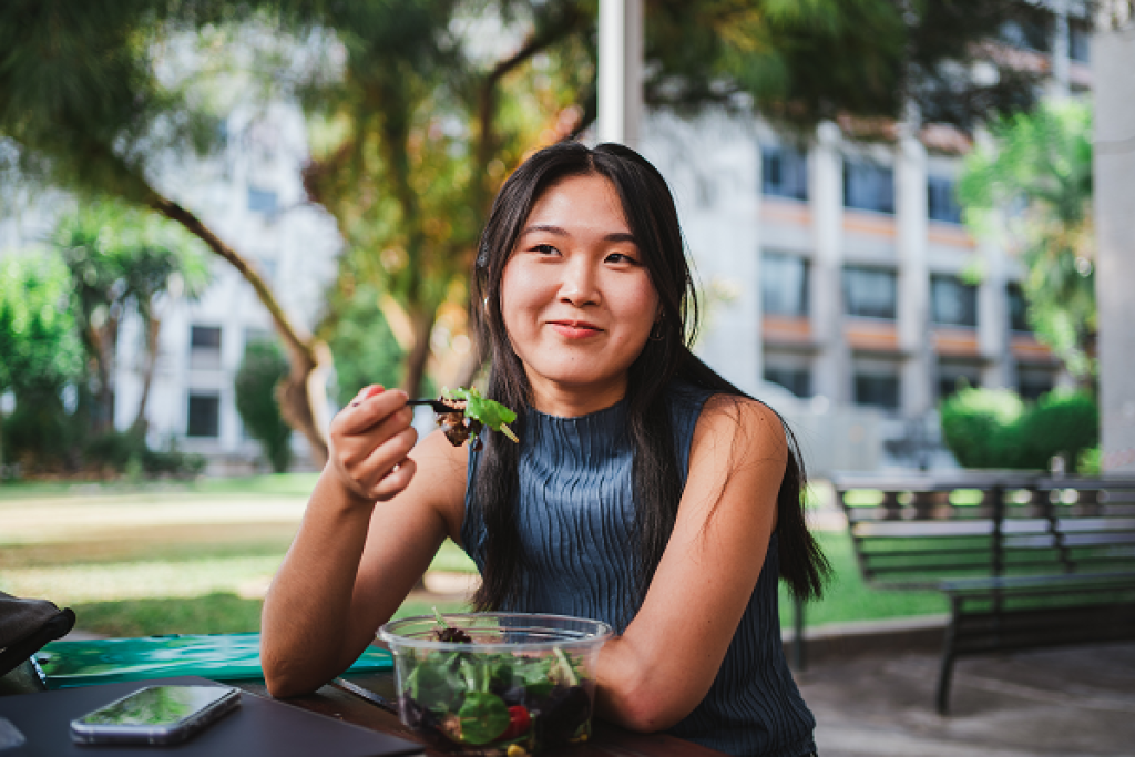 Young woman eating a salad.  Image courtesy of Adobe Stock