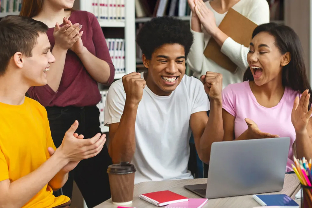 Students cheering for another student’s success, courtesy of Adobe Stock.