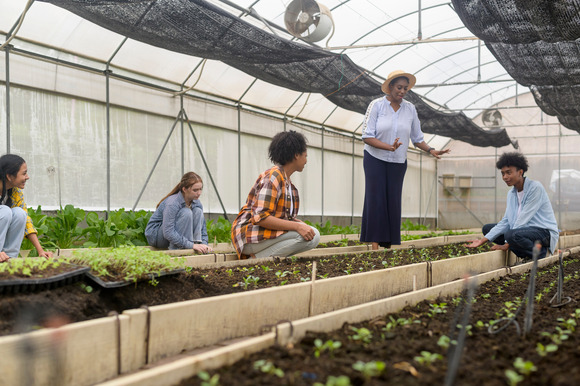 Teacher and students in greenhouse. Image courtesy of Adobe Stock.