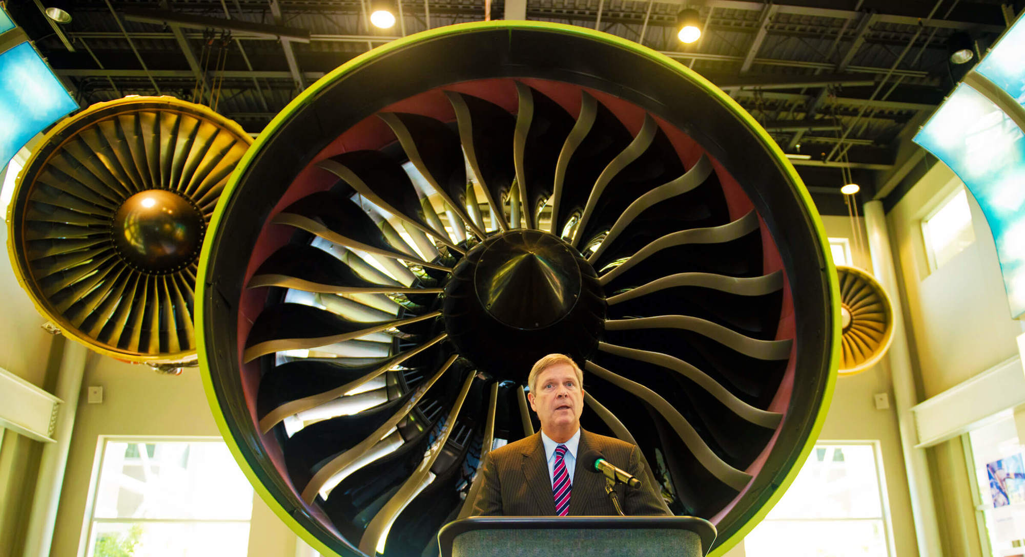 Agriculture Secretary Tom Vilsack stands in front of General Electric’s GE 90–115B, the engine that powers the Boeing 777. 