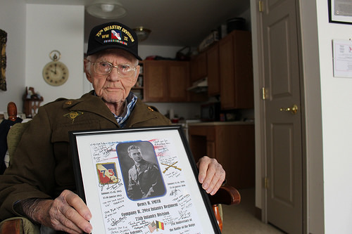 Henry Smith, who served in the 75th Infantry Division in World War II, holds a gift he received when he visited Belgium earlier this year. The framed 