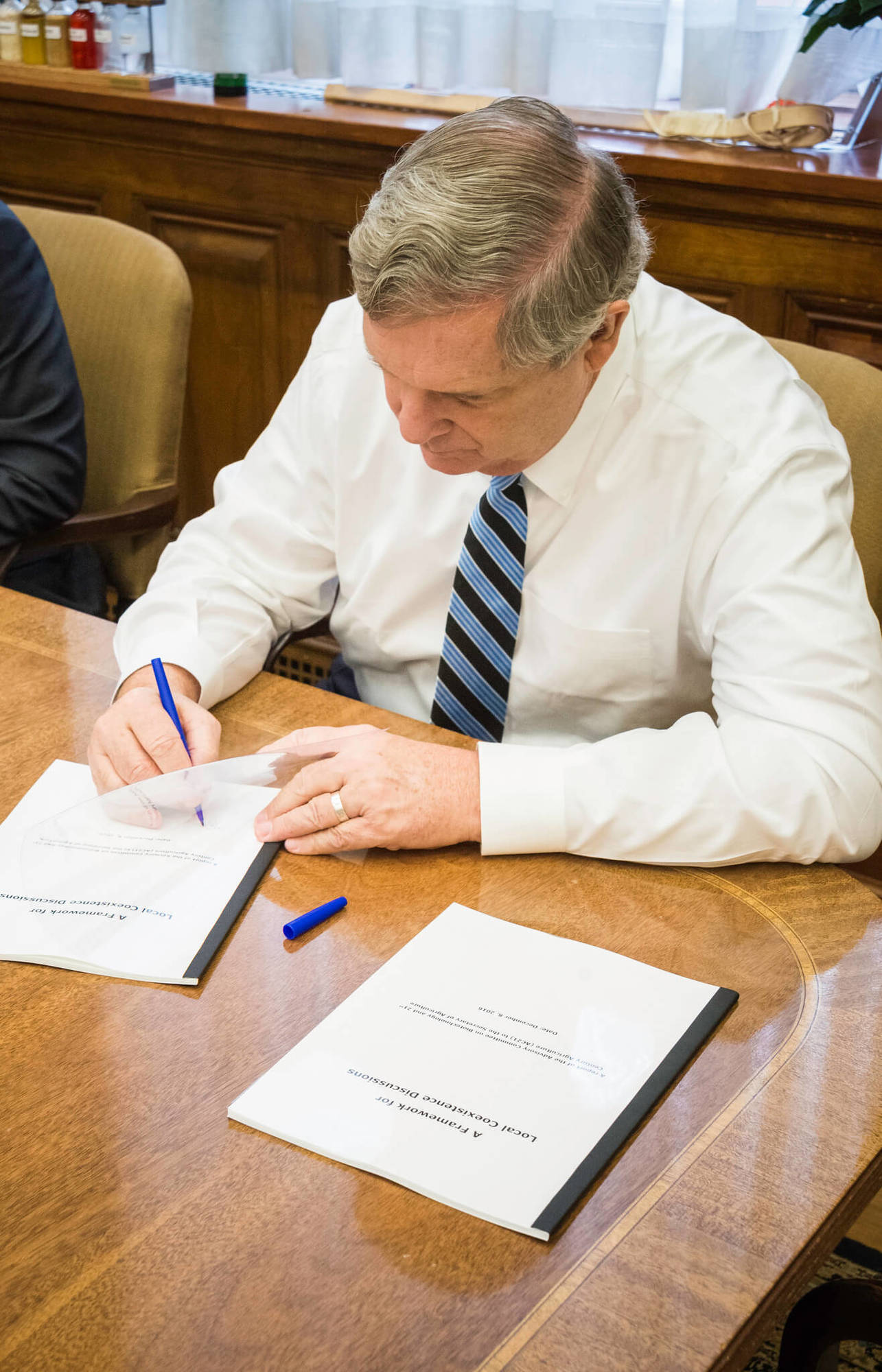 Agriculture Secretary Tom Vilsack signs copies of, “A Framework for Local Coexistence Discussions,” an important report