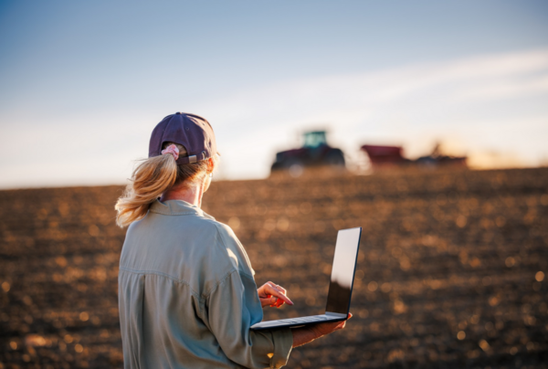 A farmer working on a laptop near a tractor