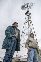 2 Black farmers standing with a windmill behind them