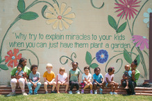Photo of women and children in front of a colorful wall with drawings of flowers and inspirational saying