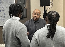 An older Black man talks with two Black students