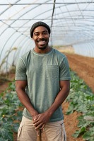 Young black man standing in a greenhouse