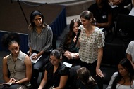 Young adults sitting and standing in an auditorium.