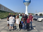 Staff and Black students stand in front of a water tower