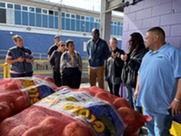 Mixed race adults at a farmers market with sacks of potatoes in the foreground