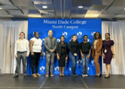 A group of mixed race students stand in front of a display