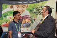 An older Hispanic Man speaks with a Hispanic teen boy at a conference