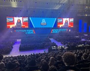 Crowded arena with projected images on state