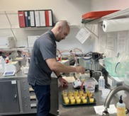 A man stands and tests orange juice in a laboratory setting