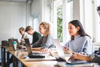 Row of students in a classroom with laptops open