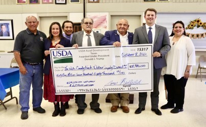 A group gathers together to celebrate the receipt of a ceremonial oversized check.