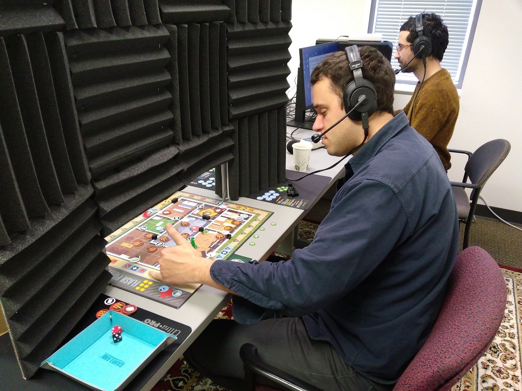 An audio engineer (wearing red pants) at the Linguistic Data Consortium at UPENN collects data from study participants who are playing board games.