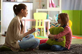 Mother and daughter sitting on floor facing each other